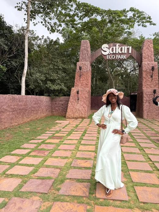 A guest in a flowing mint dress and sun hat at the entrance to Safari Eco Park.