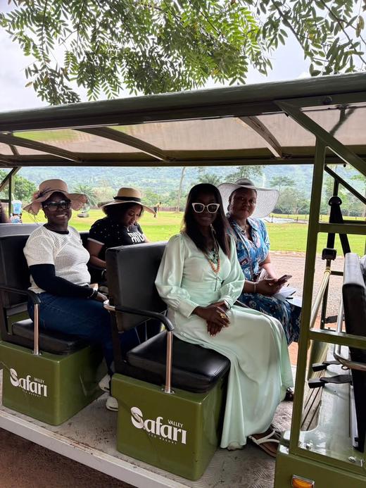 Retreat guests in sunglasses and hats riding an open safari buggy.