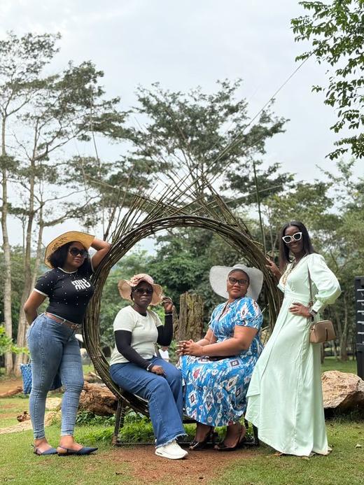 Four guests posing around a woven circular sculpture in the park.
