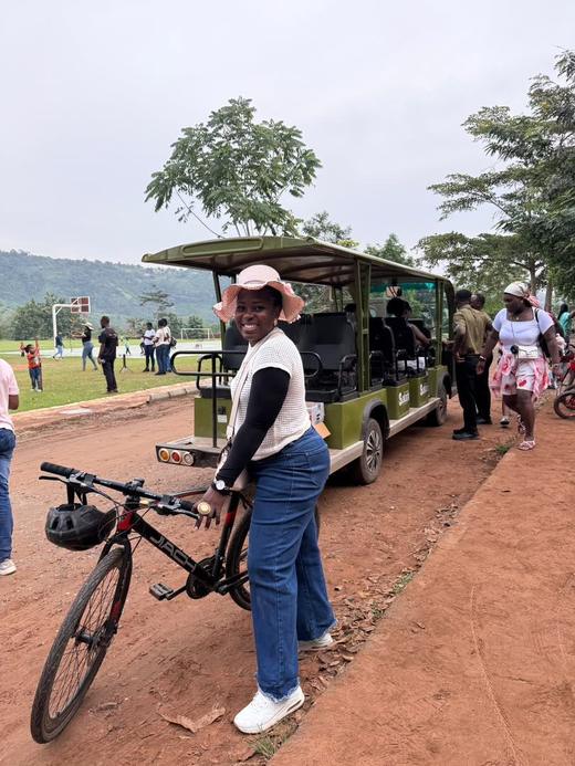 A guest standing with a bicycle on a red-earth path in the park.