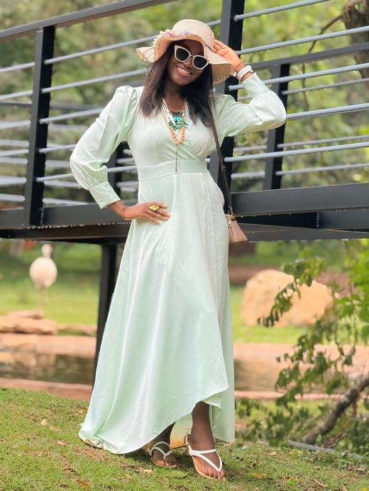 A guest in a mint dress and wide-brimmed hat posing on a viewing deck.