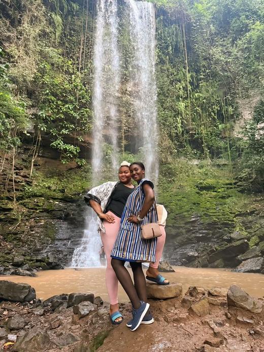 Two guests embracing in front of a tall waterfall.